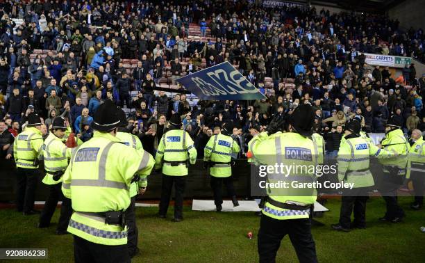 Police hold back fans during a pitch invasion after the Emirates FA Cup Fifth Round match between Wigan Athletic and Manchester City at DW Stadium on...