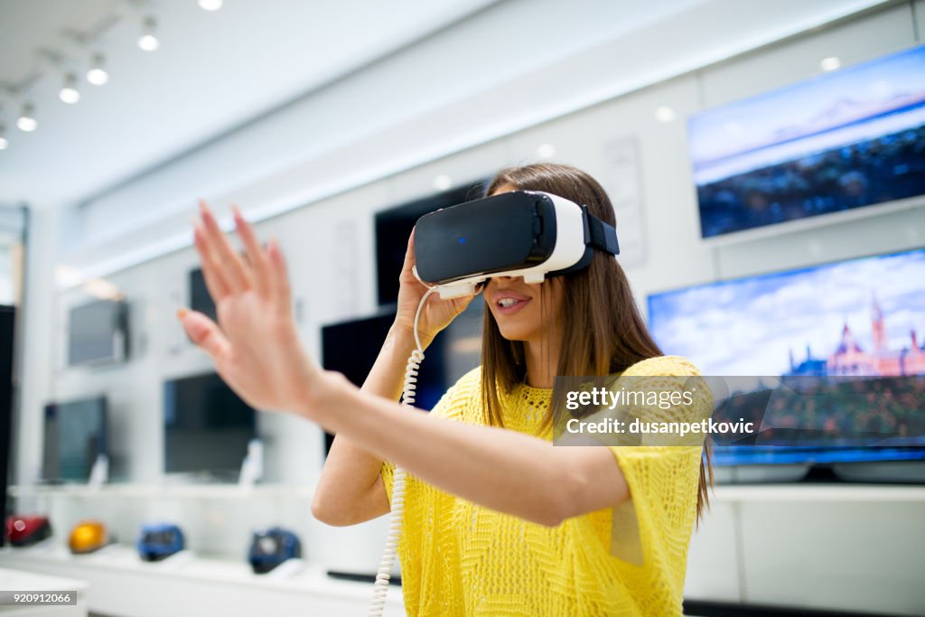 Una ragazza piuttosto giovane sta testando le cuffie VR nel negozio di elettronica.
