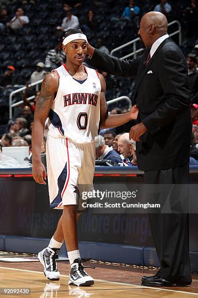 Jeff Teague of the Atlanta Hawks is greeted at the bench by head coach Mike Woodson during the preseason game against the Washington Wizards on...