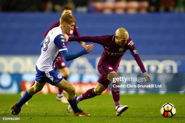 David Silva of Manchester City is challenged by Jay Fulton of Wigan Athletic during the Emirates FA Cup Fifth Round match between Wigan Athletic and...