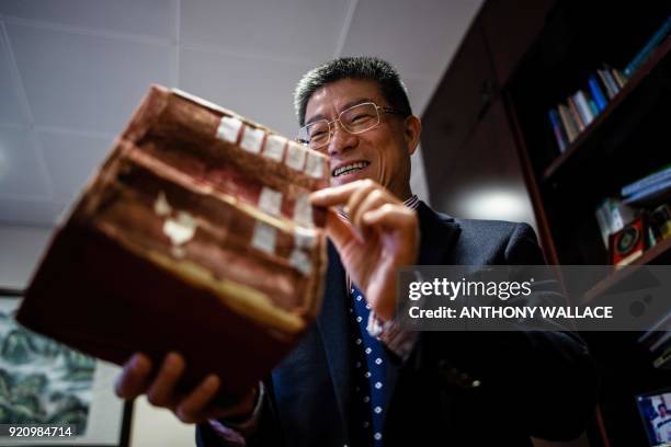 In this picture taken on February 2 professor Lei Heong Iok holds what he calls "his treasure", a Portuguese dictionary, in his office at the Macau...