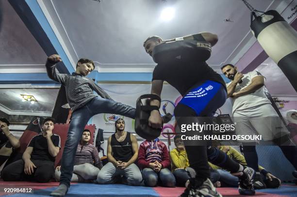 Syrian refugee Amir al-Awad watches as Adel Bazmawi teaches martial arts to youth at the academy in Egypt's second city of Alexandria on January 4,...
