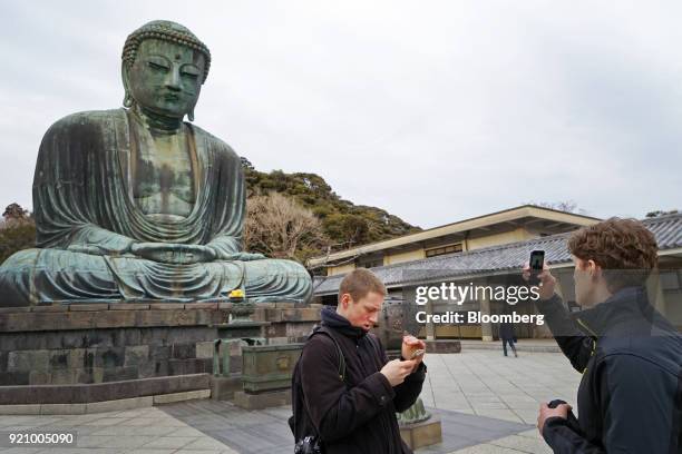 Tourists take photographs with their smartphones in front of the Great Buddha at the Kotokuin temple in Kamakura, Kanagawa, Japan, on Monday, Feb....