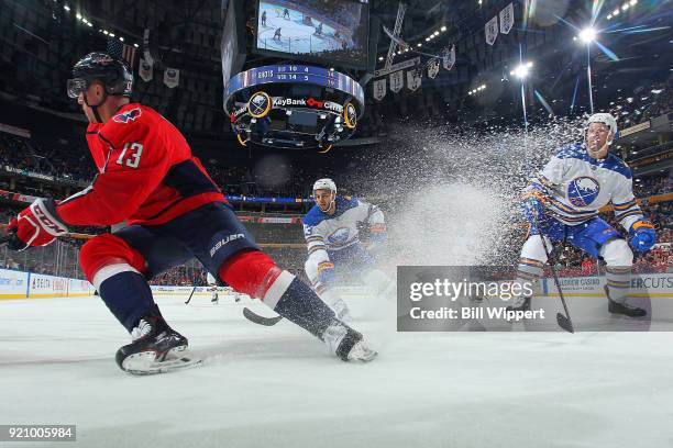 Jakub Vrana of the Washington Capitals turns with the puck against Nicholas Baptiste and Josh Gorges of the Buffalo Sabres during an NHL game on...