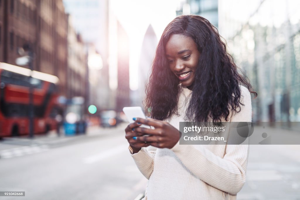 Hermosa mujer negro, uso de teléfono en el centro para llamar taxi crowdsourcing