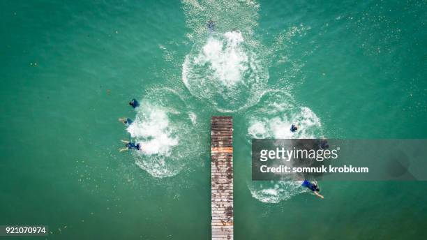 Aerial view jumping boy into clear sea water in summer by drone