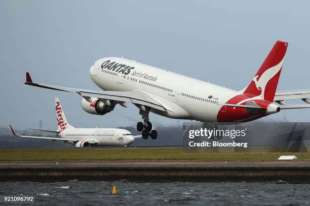 An Airbus SE A330-300 aircraft operated by Qantas Airways Ltd., right, takes off as an aircraft operated by Virgin Australia Holdings Ltd. Taxies on...