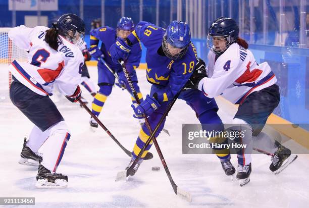 Anna Borgqvist of Sweden battles for the puck with Yujung Choi and Un Hyang Kim of Korea in the second period during the Women's Classifications game...