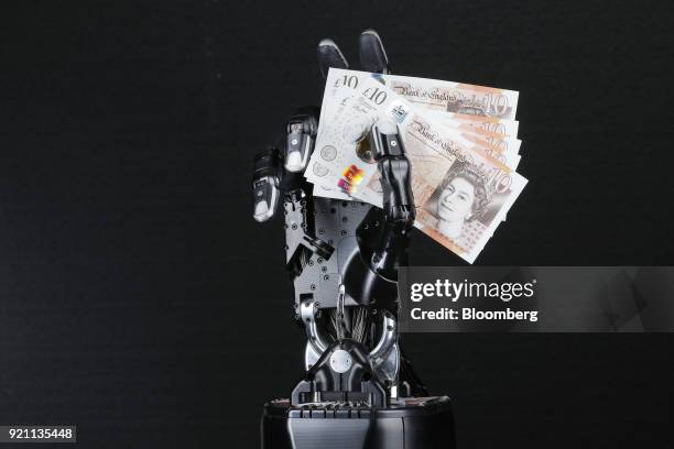 The Shadow Dexterous robotic hand, manufactured by The Shadow Robot Company, holds a set of the British polymer ten pound sterling banknotes during a...