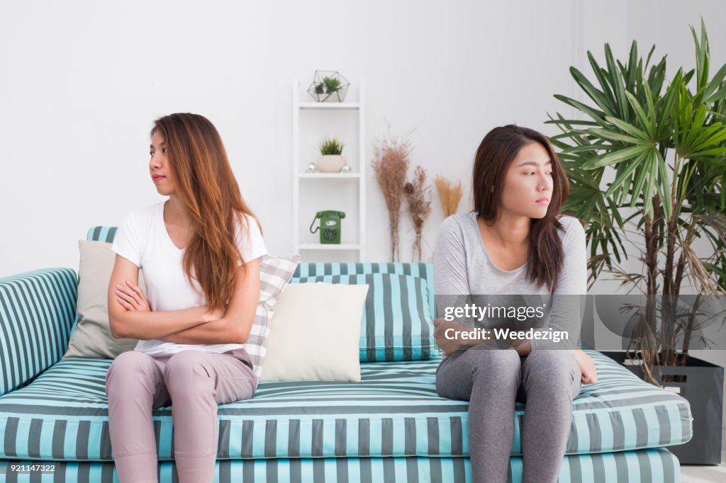 Asia lesbian lgbt couple quarrel sitting each side of sofa with moody emotion in living room.