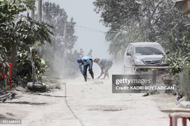 Men clean volcanic ash from the street after Mount Sinabung volcano spewed thick volcanic ash across the area the day before in Karo, North Sumatra...
