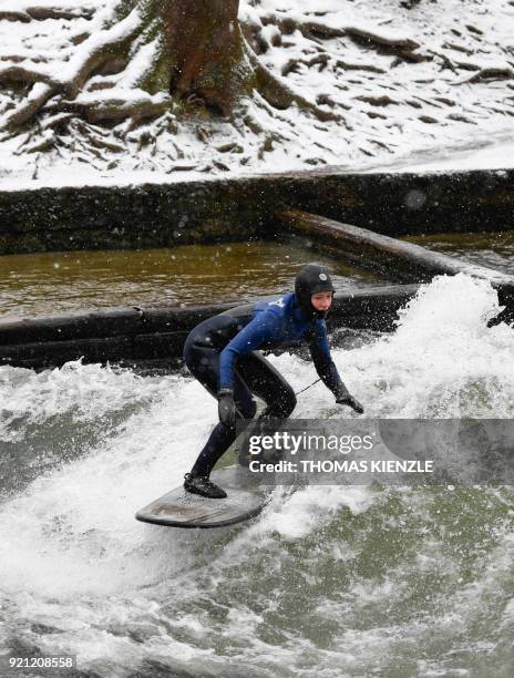 Woman surfes the wave on the Eisbach creek in the English Garden in Munich, southern Germany, on February 20, 2018. / AFP PHOTO / THOMAS KIENZLE