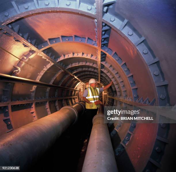 water engineer examining a large underground metal pipe system - oil pipeline stock pictures, royalty-free photos & images