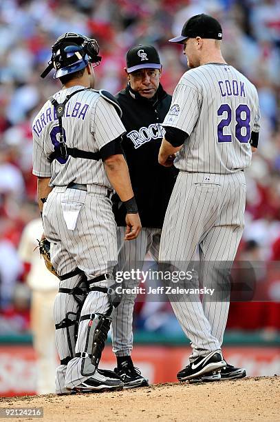 Pitching coach Bob Apodaca of the Colorado Rockies talks with catcher Yorvit Torrealba and Aaron Cook against the Philadelphia Phillies in Game Two...