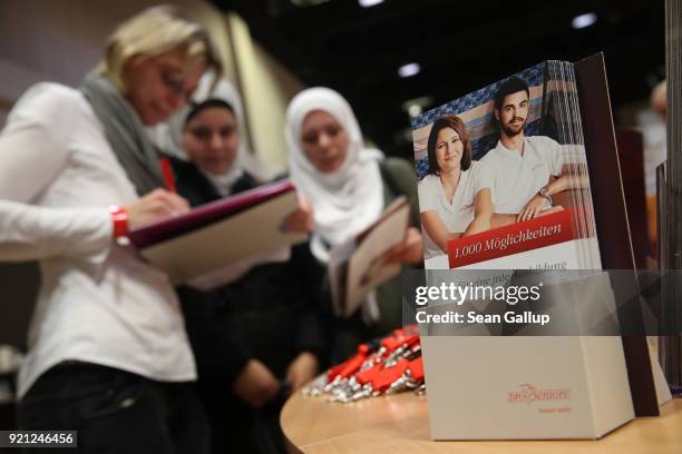 Hostess at a stand of German senior care facility provider Pro Seniore explains employment opportunities to two young women from Syria at the annual...