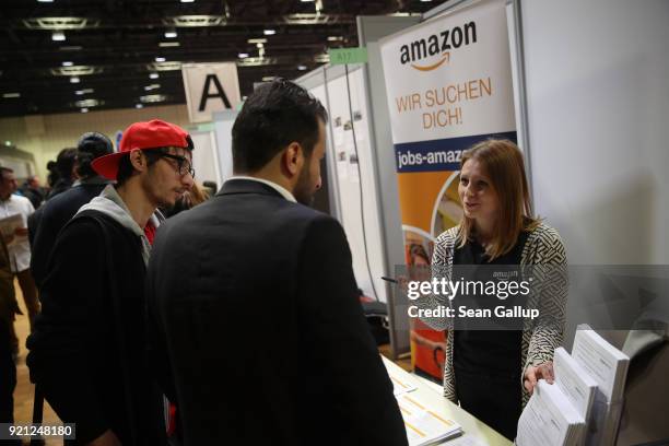 Hostess at a stand of online retailer Amazon explains employment opportunities to job seekers at the annual jobs fair for refugees and migrants at...