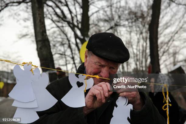 Crying man hangs a paper cutted angels at the Memorial with a portraits of mass shootings victims. Ukraine pays tribute to the victims of the...