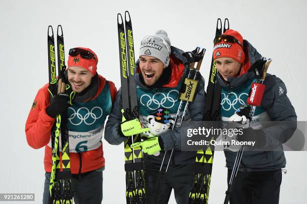 Johannes Rydzek of Germany celebrates winning the gold medal with silver medallist Fabian Riessle of Germany and bronze medallist Eric Frenzel of...