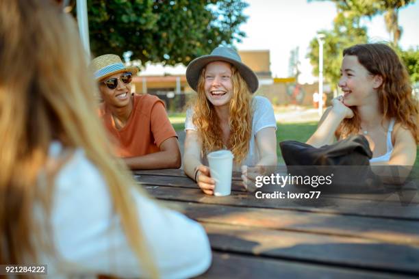 young friends sitting in the park and talking - teens stock pictures, royalty-free photos & images