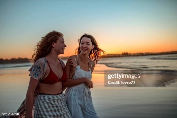 young friends walking at the coastline at sunset - gold coast queensland stock pictures, royalty-free photos & images