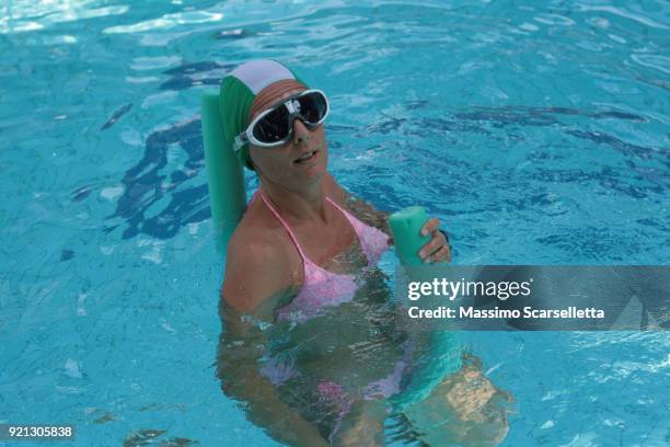 european woman relaxing in pool sitting on pool noodle - piscina ストックフォトと画像
