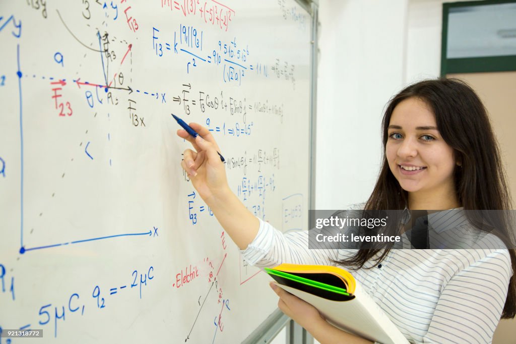 Studentin, die mathematische Formel vor dem Whiteboard schreiben