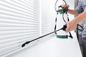 Worker Spraying Insecticide On Windowsill