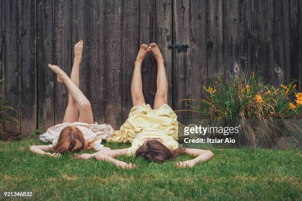 two sisters lying on the grass - happy tween girls lying on grass stock pictures, royalty-free photos & images