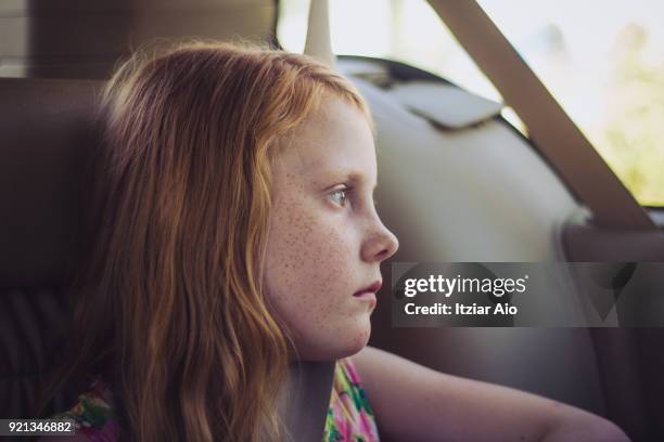 girl in the back seat of the car wearing seat belt.looking at view - freckle girl stock pictures, royalty-free photos & images