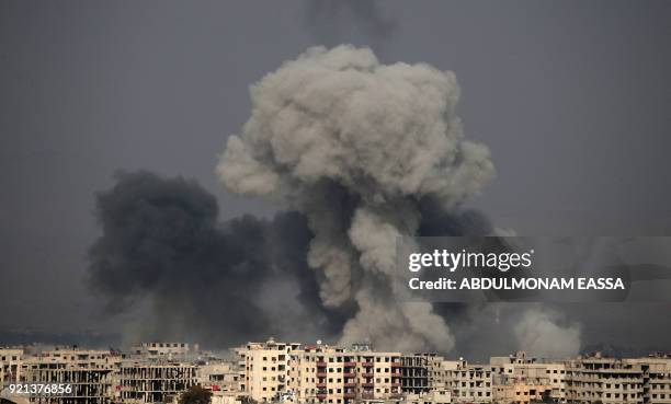 Picture taken on February 20, 2018 shows smoke plumes rising following a reported regime air strike in the rebel-held town of Hamouria, in the...