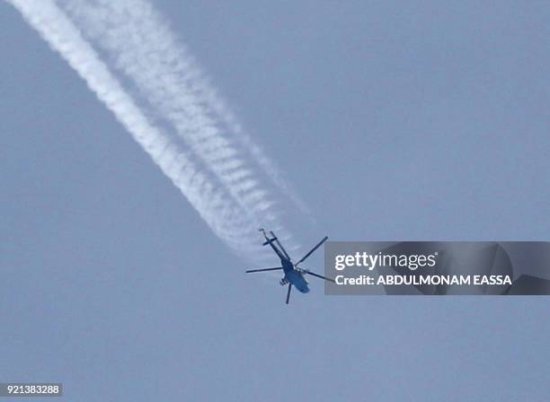 Picture taken on February 20, 2018 shows a Russian-made Syrian army attack helicopter flying over the sky in the rebel-held town of Saqba, in the...