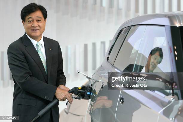 Mitsubishi Motors Corp. President Osamu Masuko poses with the company's concept plug-in hybrid electric vehicle 'PX-MiEV' during the 41st Tokyo Motor...