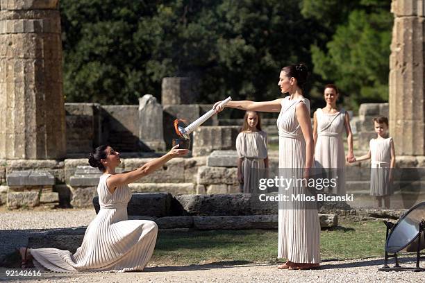 Maria Nafplotou , who plays the role of high priestess passes the flame from the olympic torch at the Ancient Olympia site during a rehearsal for the...