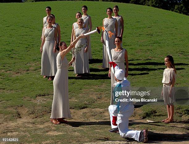 Maria Nafplotou , who plays the role of high priestess, passes the olympic flame to skier Vassilis Dimitriadis, the first torchbearer, during a...