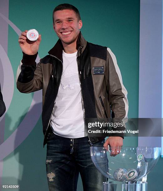 Lukas Podolski of FC Koeln smiles with the Bayern Muenchen logo drawing the Women's DFB Cup round of sixteen matches during the DFB press conference...