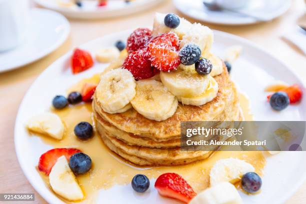 close-up of delicious pancakes with fresh fruits, berries and maple syrup on a plate - blueberry pancakes stock pictures, royalty-free photos & images