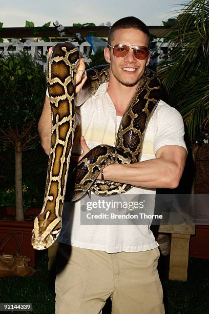 Nacho Pop poses with a Burmese Python during the VIP Launch of the Opera Bar's "The Best Beer Garden in the World" installation bar, which will be in...