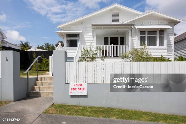 external shot of wooden villa from street with 'for sale' sign - morgage stockfoto's en -beelden