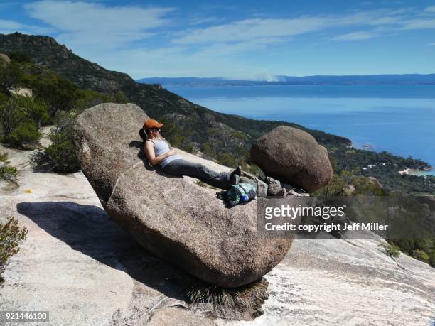 woman reclining on granite rock, freycinet national park, tasmania - freycinet foto e immagini stock