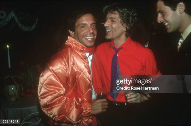 American businessman and Studio 54 nightclub owner Steve Rubell , dressed in a quilted, salmon-colored satin jacket smiles as he stands and drinks...