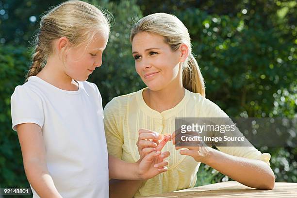 woman putting plaster on daughter - applying plaster stock pictures, royalty-free photos & images