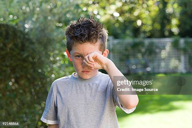 boy rubbing eye - seasonal sadness stock pictures, royalty-free photos & images