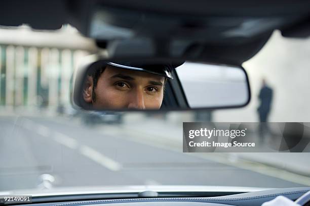 chauffeur looking in rear view mirror - chauffeur stock pictures, royalty-free photos & images