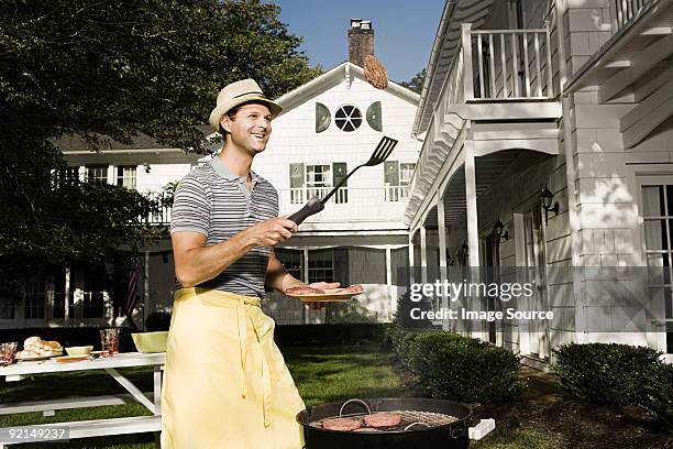 man cooking on a barbecue - gooien stockfoto's en -beelden