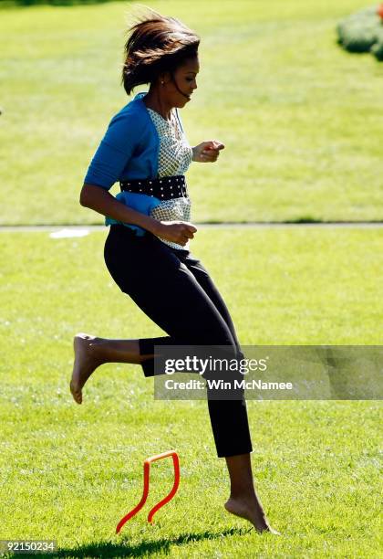 First lady Michelle Obama runs barefoot on an obstacle course on the South Lawn of the White House during an event promoting exercise and healthy...