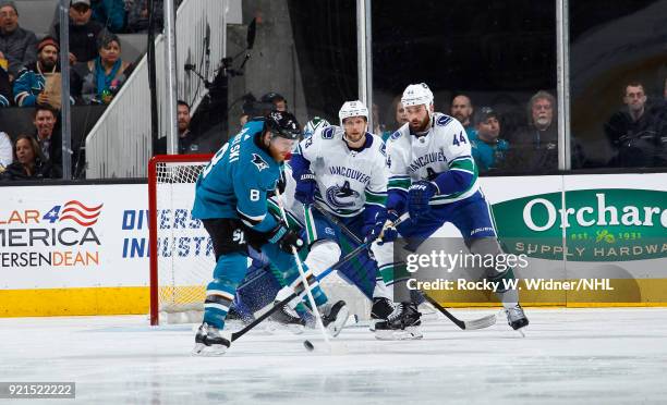 Joe Pavelski of the San Jose Sharks skates with the puck against Alexander Edler and Erik Gudbranson of the Vancouver Canucks at SAP Center on...