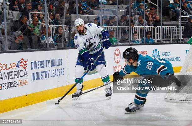 Erik Gudbranson of the Vancouver Canucks skates with the puck against Timo Meier of the San Jose Sharks at SAP Center on February 15, 2018 in San...