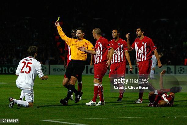 Thomas Muller of Bayern Muenchen receives his first yellow card from Referee Terje Hauge during the UEFA Champions League Group A match between...