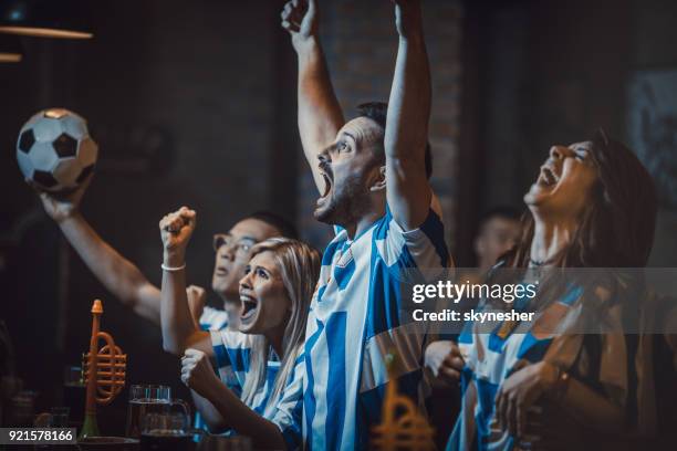 groep van opgewonden voetbal fans kijken succesvolle wedstrijd op een tv in een bar. - een doelpunt maken stockfoto's en -beelden