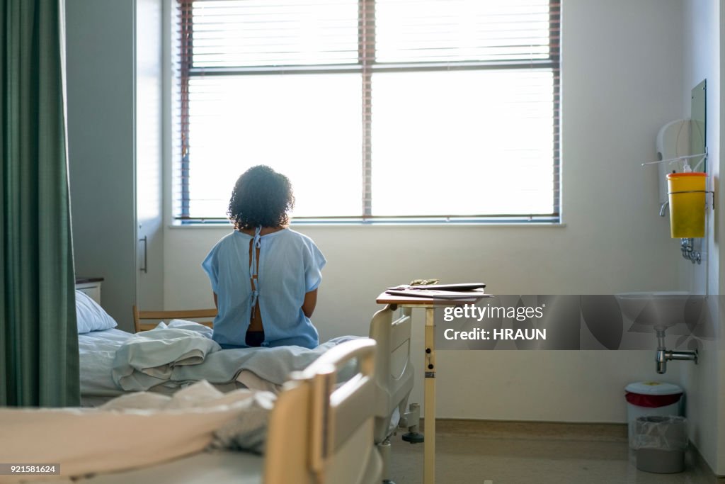 Lonely female patient sitting on hospital bed